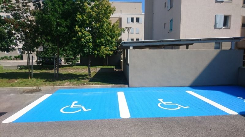 Traçage de pictogramme PMR sur fond bleu pour places de parking à Salon