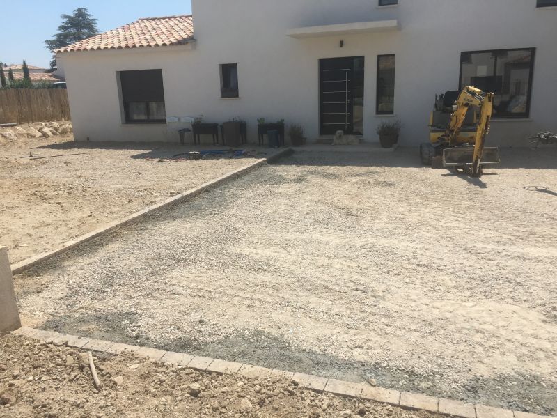 Pose des pavés sur lit de béton bordant une entrée de villa en béton désactivé